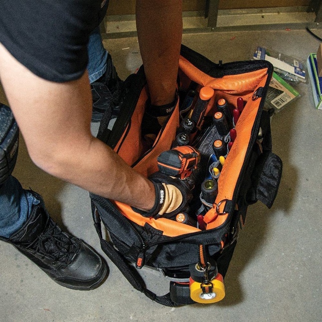 A person putting tools in a bag</p>
<p>Description automatically generated